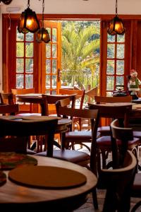 een restaurant met tafels, stoelen en ramen bij Hotel Pousada Arcádia Mineira in Ouro Preto