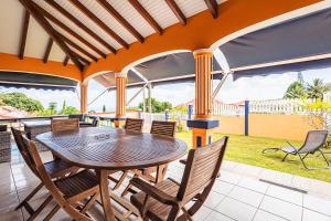 un tavolo e sedie in legno su un patio di Villa Sofaia à sainte-rose, 9 pers, 3 chambres, vue mer et montagne, piscine privée a Sainte-Rose