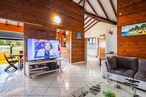 un soggiorno con TV e divano di Villa Sofaia à sainte-rose, 9 pers, 3 chambres, vue mer et montagne, piscine privée a Sainte-Rose