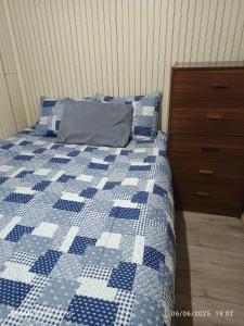 a bed with a blue and white quilt and a dresser at Casa en arriendo in Quintero
