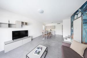 een woonkamer met een tv, een bank en een tafel bij Villa Prestige in Sirmione