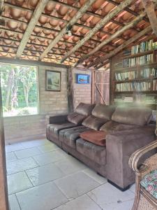 ein großes braunes Sofa in einem Zimmer mit einem Bücherregal in der Unterkunft Casa rústica divertida in Florianópolis + 19 Fotos