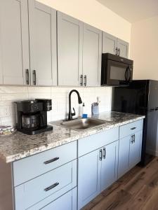 una cucina con mobili bianchi, un lavello e un microonde di Waena Inn Unit 2 Newly Renovated Maui Private Suite a Wailuku