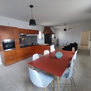 eine Küche und ein Esszimmer mit einem roten Tisch und weißen Stühlen in der Unterkunft De Uait Aus in Fossalta di Piave