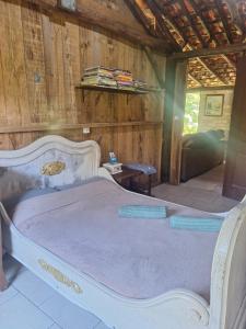 ein weißes Bett in einem Zimmer mit einer Holzwand in der Unterkunft Casa rústica divertida in Florianópolis