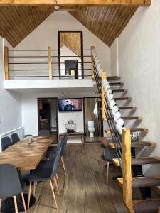 a dining room with a table and a spiral staircase at EDANT HOUSE in Bumbesti Pitic
