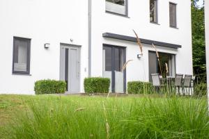 a white house with chairs in the grass at Strandhaus Meeresperle in Ostseebad Sellin