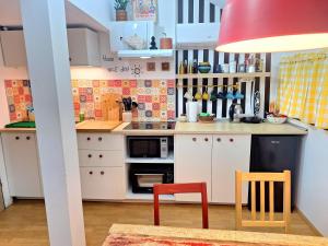 a small kitchen with white cabinets and red chairs at Boho House 5 camp Terme Catez with promotional tickets prices in Čatež ob Savi