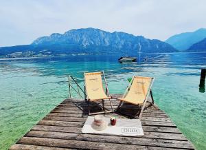 阿特湖畔翁特拉赫洛茵德尔公寓酒店的码头上的两把椅子,船上有一条船