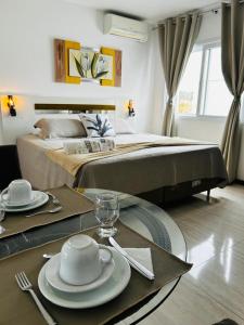 a room with a table with plates and a bed at La Plage Residence in Garopaba