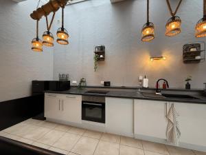 a kitchen with white cabinets and a sink and lights at Loft Des Sens in Saint-Chamond