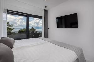 een slaapkamer met een wit bed en een groot raam bij Luxury Sea View Villa DIJANA with Infinity Pool & Jacuzzi Near Rijeka in Kostrena