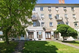 a large white building with trees in front of it at GrandPa Delux in Miskolc