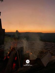 een vuurplaats met de zonsondergang op de achtergrond bij Rancho Sol Poente - Rancho Queimado - SC in Rancho Queimado