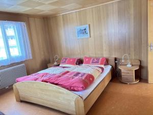 a bedroom with a large bed with pink sheets and pillows at Easy Central Stay with Parking in Grächen
