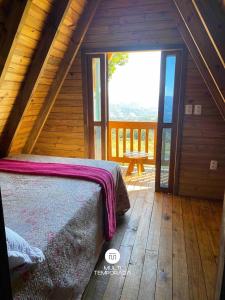 een slaapkamer met een bed in een houten hut bij Rancho Sol Poente - Rancho Queimado - SC in Rancho Queimado