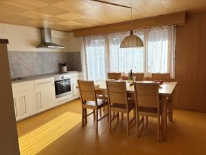a kitchen with a wooden table and chairs in a kitchen at Easy Central Stay with Parking in Grächen