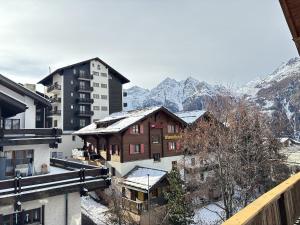 a view of a town with snow covered buildings and mountains at Easy Central Stay with Parking in Grächen