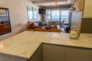 a kitchen and living room with a view of the ocean at Dookes Apartment in Umdloti