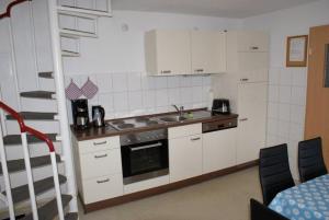 a kitchen with white cabinets and a sink and a staircase at Ferienhaus Thiess - ABC402 in Wismar