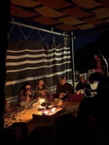 a group of people sitting around a fire in a tent at Wadi Rum Mars Camp in Wadi Rum