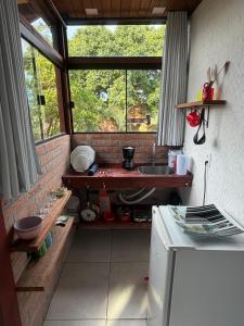 eine kleine Küche mit Spüle und Fenster in der Unterkunft Loft no centrinho do Rosa in Imbituba