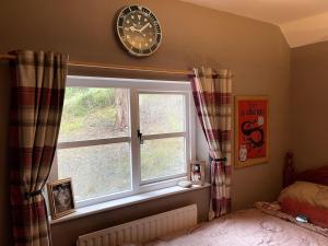 a window in a bedroom with a clock on the wall at Bear Cottage in Scyborycoed