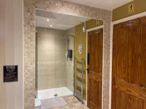 a bathroom with a shower and a glass door at Bear Cottage in Scyborycoed +22 photos