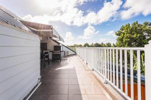 an outdoor balcony with a white fence and a table at appartement haut standing au grands fonds du moule, 6 pers, très spacieux in Le Moule