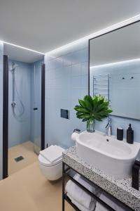 a bathroom with a white sink and a toilet at ROOMA Apartments in Vilnius