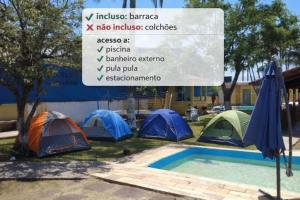 een groep tenten en een bord naast een zwembad bij Pousada Perolas de Itanhaem in Itanhaém