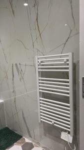 een badkamer met witte marmeren muren en een radiator bij Duplex appartement in Étampes