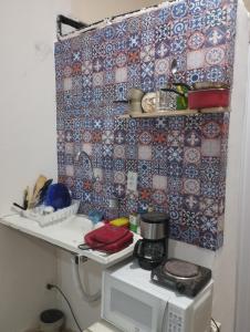 eine Küche mit Mikrowelle und einer Wand mit Fliesen in der Unterkunft Casa na melhor localização de Santa Teresa in Rio de Janeiro