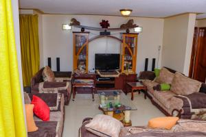 a living room with couches and a flat screen tv at Prissy Apartment in Nairobi