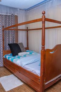 a bed with a wooden bed frame in a room at Prissy Apartment in Nairobi