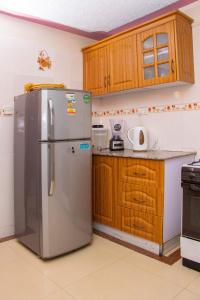 a kitchen with a stainless steel refrigerator and wooden cabinets at Prissy Apartment in Nairobi +8 photos