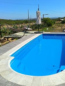 a blue swimming pool with a table and a umbrella at Las 3 parcelas in El Manzano