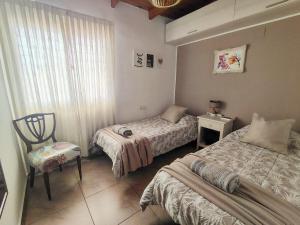 a room with two beds and a chair in it at Depto Viamonte PlantaAlta, 2Dorm, Terraza, Cochera in Cordoba