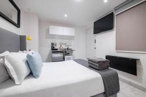 a bedroom with a large white bed and a kitchen at Casa Ama in Mexico City