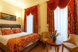a bedroom with a bed and a chair and windows at BeyPort Hotel Istanbul in Istanbul