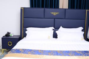un letto con testiera blu e cuscini bianchi di Mpaata Empire Royal Suites a Hoima