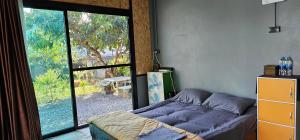 a bedroom with a bed and a large window at ST house in Ban Nua Khlong