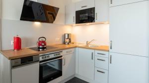 a kitchen with white cabinets and a red appliance at Kiel Water 4 in Schilksee +13 photos