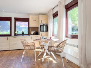 a kitchen with a table and chairs and windows at Haus am Strand in Zingst
