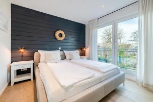 een slaapkamer met een groot bed en een groot raam bij Haus am Siel 02 in Greetsiel
