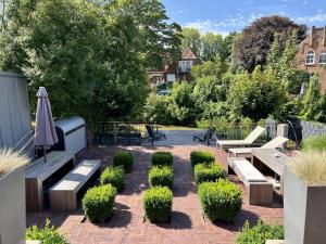 een patio met banken, een parasol en struiken bij Haus am Siel 02 in Greetsiel