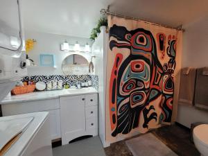 a bathroom with a shower curtain with a painting on it at Nesting Ravens cottage in Nanaimo +15 photos