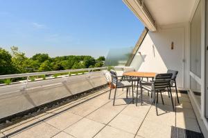 een terras met een tafel en stoelen op een balkon bij Strandläufer in Schilksee