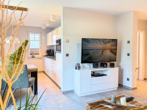 ein Wohnzimmer mit Fernseher und eine Küche in der Unterkunft Meerle 3 in Zingst
