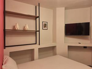a bedroom with a flat screen tv and shelves at Adhoc Fundidora in Monterrey